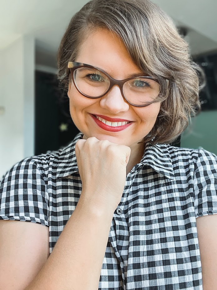 Klaudia smiling in glasses, wearing a checked shirt